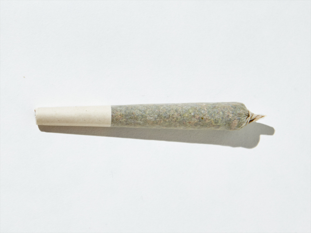 A small white tube with a green tip, representing a joint, illustrating how to smoke weed effectively.